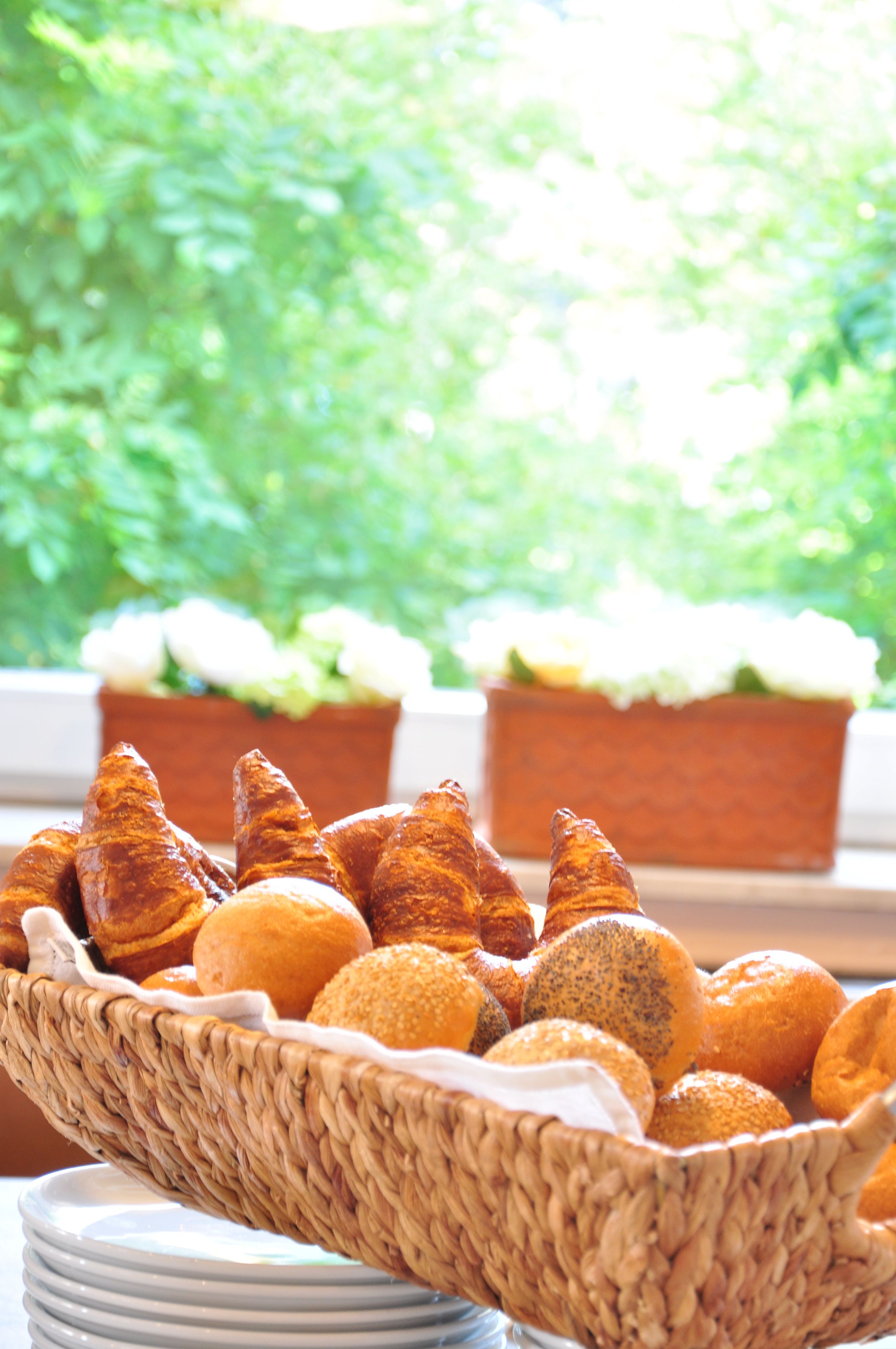 A basket of assorted pastries on a table with a window view.