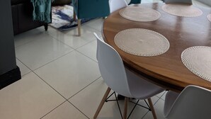 Ein moderner Essbereich mit einem runden Tisch, weißen Stühlen und Meerblick durch große Fenster.