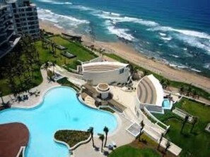 Ein Resort mit großem Pool, direkt am Strand und einem runden Gebäude.
