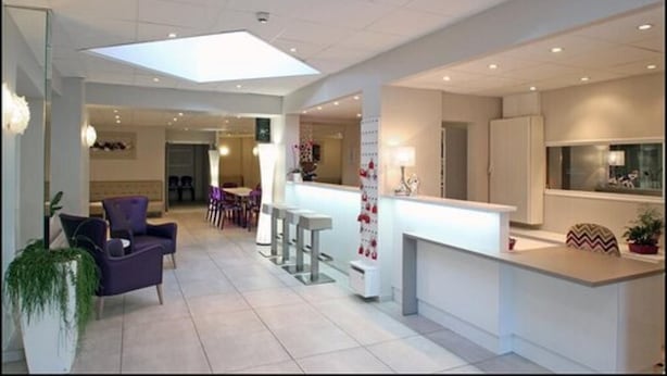 Un intérieur moderne avec un îlot central servant de comptoir, un coin salon et une verrière.
