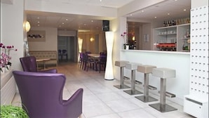 Un intérieur moderne avec un espace bar, des sièges et un comptoir d’accueil bien visible.