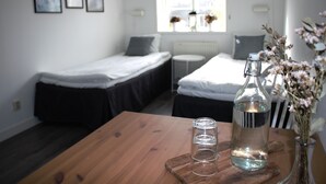 Un dormitorio con cama, mesita de noche y ventana con flores.