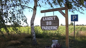 Un letrero de madera con la inscripción "LANDET BB PARKERING" y un símbolo de estacionamiento.