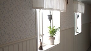 Un pasillo con ventana, una planta en maceta y una lámpara colgante.