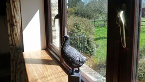 A view from a window with a wooden sill, a metal railing, and a statue of a bird. - Cameley Lodge (Bristol)