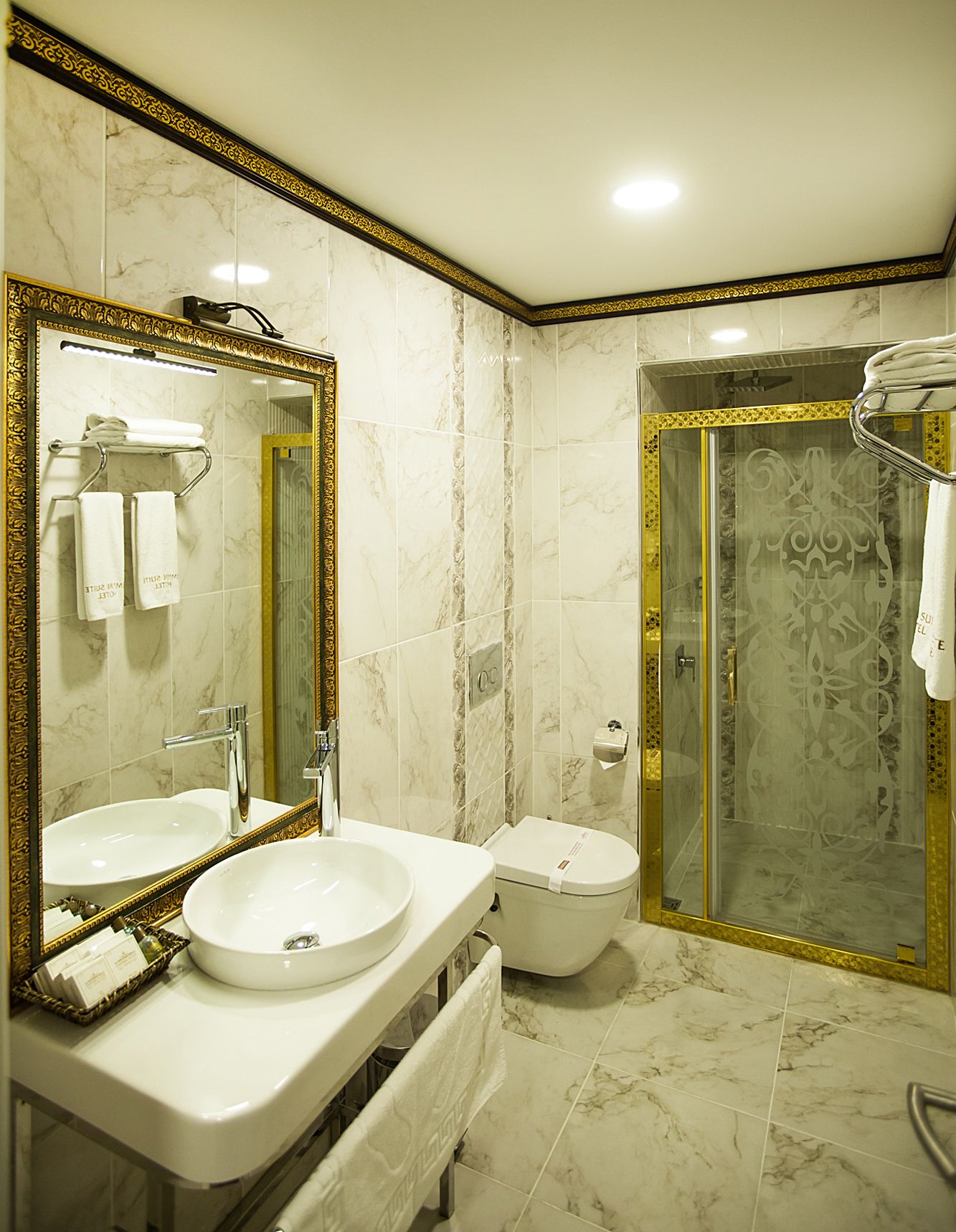 Une salle de bain dotée d’un grand miroir, de deux lavabos, de toilettes et d’une douche à parois de verre.