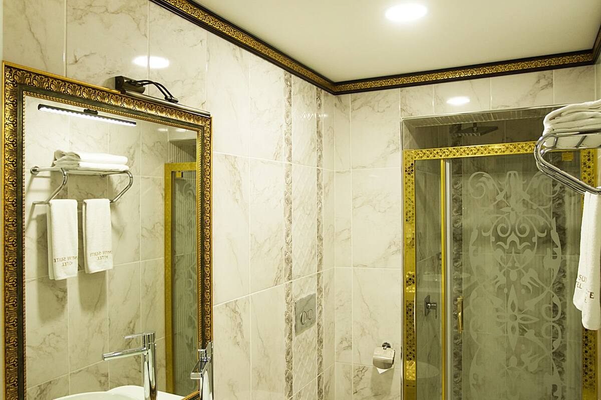 A bathroom with a large mirror, two sinks, a toilet, and a glass-enclosed shower.