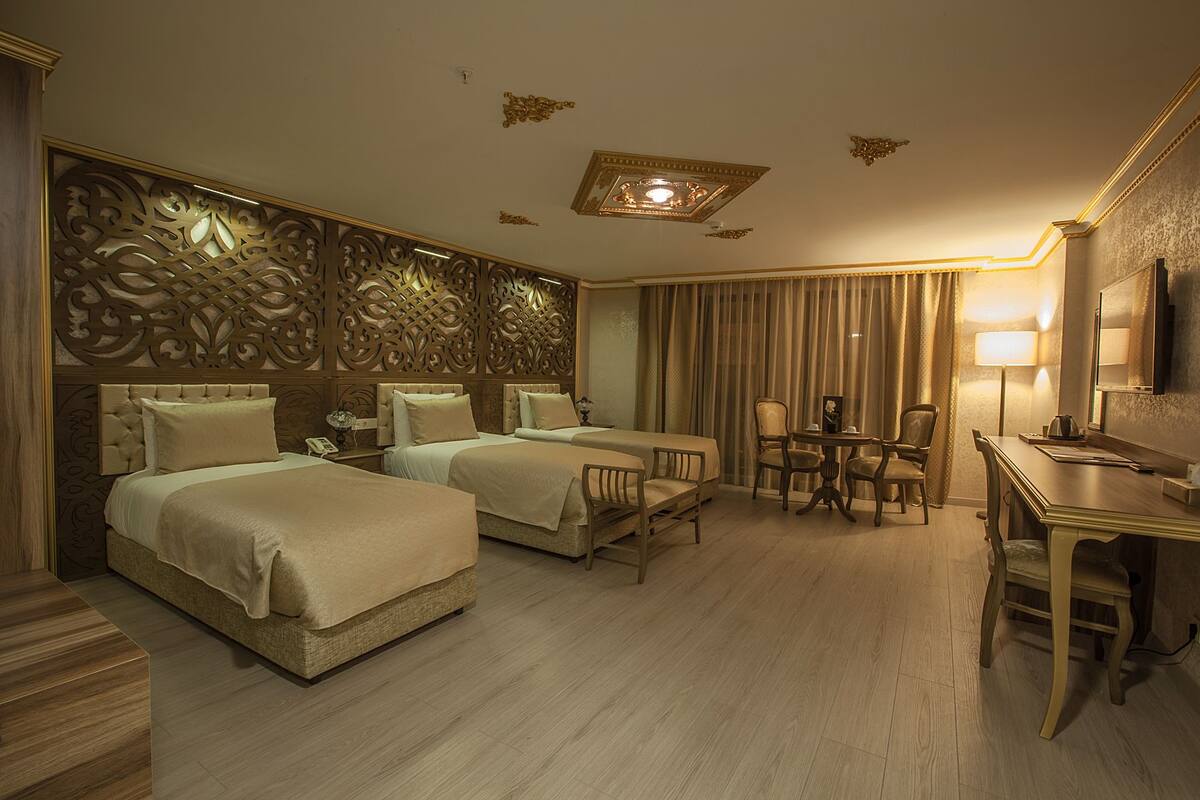 A hotel room with two beds, a desk, a chair, a table, and a mirror.