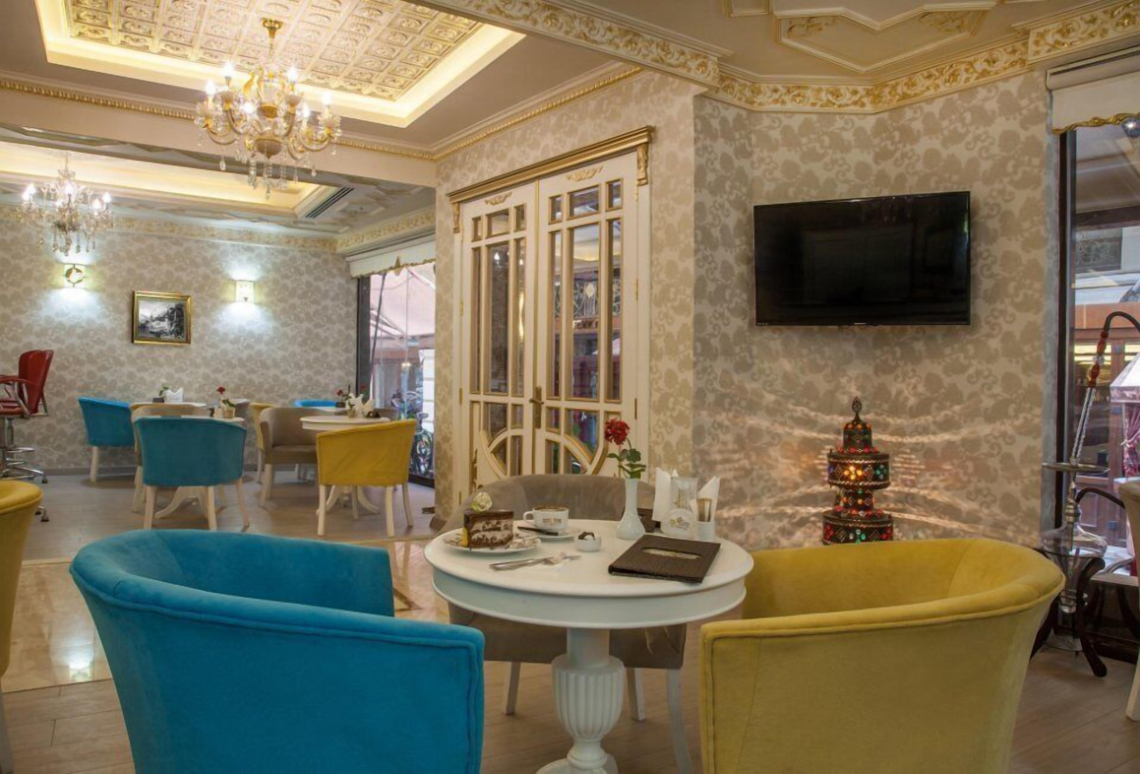 A dining area with round tables, chairs, and a chandelier.