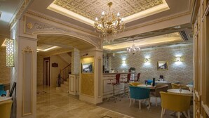 A spacious lobby with a grand chandelier, a reception desk, and a dining area with modern chairs. - Empire Suite Hotel (Istanbul)
