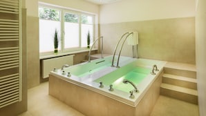 A modern bathroom with a rectangular bathtub, a window with plants, and a staircase.