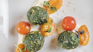 Un plato con comida que incluye hamburguesas verdes, tomates cherry y una salsa cremosa.