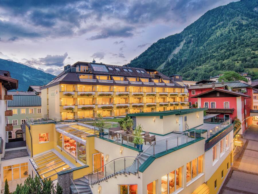 Ein mehrstöckiges Hotel mit Balkonen, einem Glasatrium und einer Bergkulisse.
