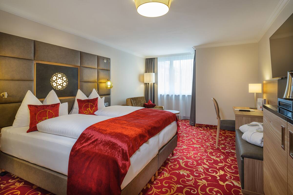 A hotel room with a large bed, a desk, and a chair.