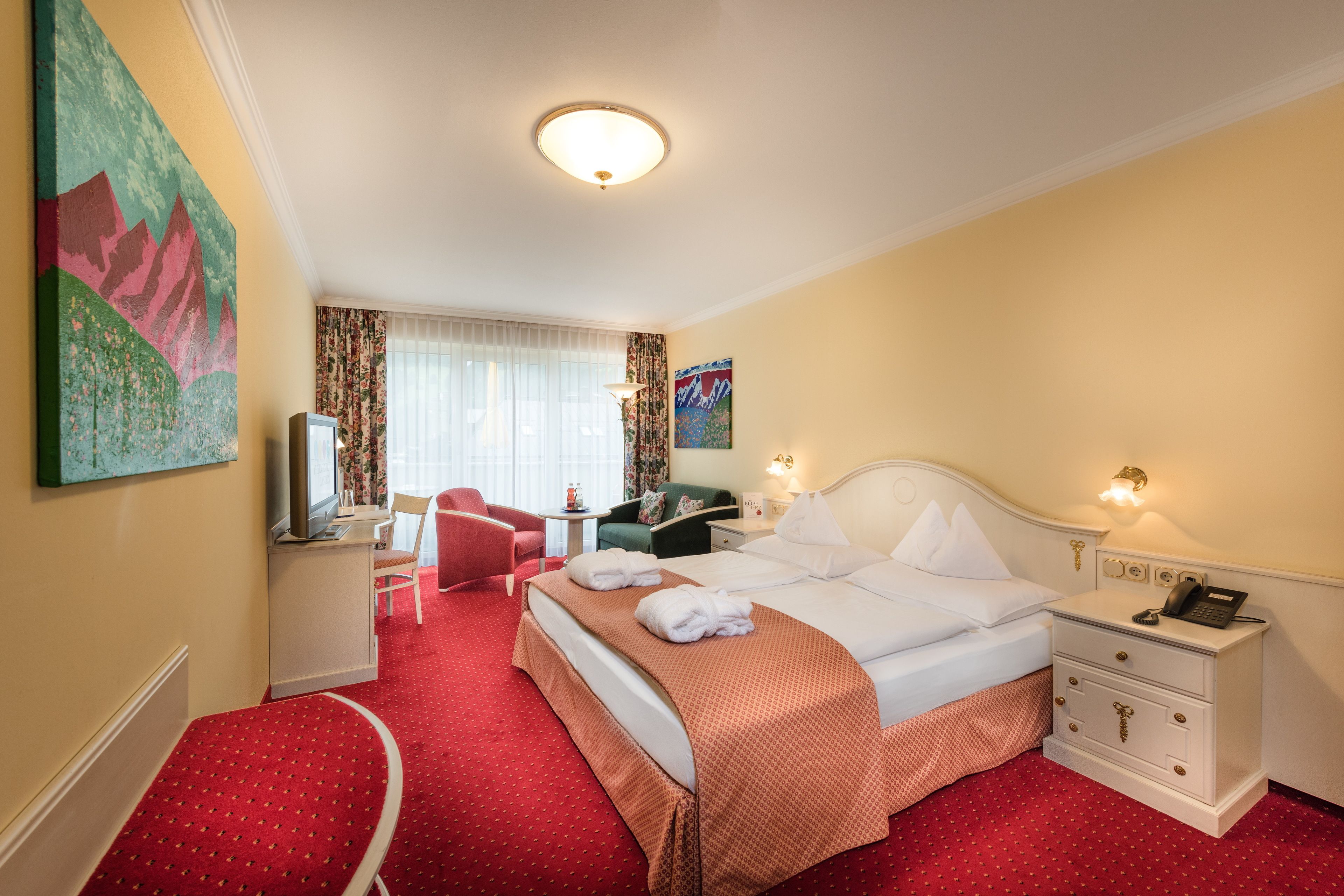 Une chambre d’hôtel comprenant un lit, une table de chevet, une chaise, un bureau et un téléviseur.