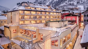 A hotel with multiple floors, balconies, and a dining area with tables and chairs.
