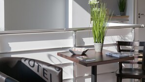 A modern hotel room with a balcony, a wooden table, a chair, and a potted plant. - Hotel Foch Nancy Centre Gare (Nancy)