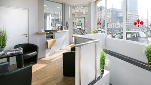 A modern hotel lobby with a reception desk, seating area, and a view of the city through large windows. - Hotel Foch Nancy Centre Gare (Nancy)