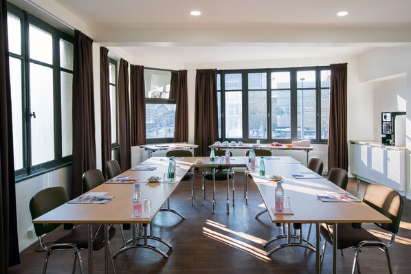 A conference room with a long table, chairs, and large windows with curtains. - Hotel Foch Nancy Centre Gare (Nancy)