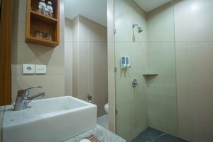 A bathroom with a bathtub, a shower, and a shelf with toiletries.