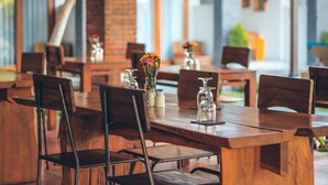 A restaurant with wooden tables and chairs, some with flowers and glassware. - Kubu Cempaka Seminyak Hotel (Seminyak)