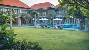 A hotel courtyard with a swimming pool, lounge chairs, and umbrellas. - Kubu Cempaka Seminyak Hotel (Seminyak)
