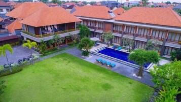 Um edifício residencial com piscina, gramados verdes e área externa coberta.