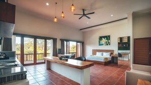 A spacious room with a kitchen area, a dining table, a bed, and a desk. - Kubu Cempaka Seminyak Hotel (Seminyak)