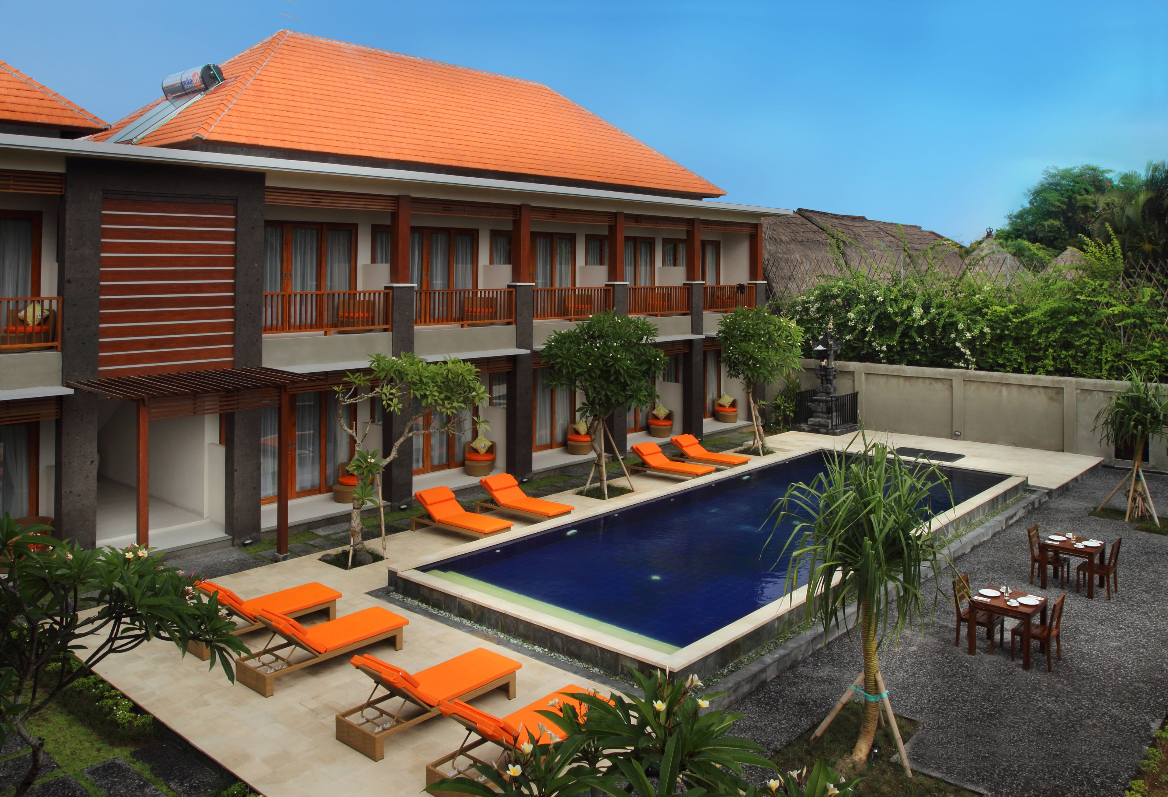 A hotel with a swimming pool, outdoor seating, and a garden area.