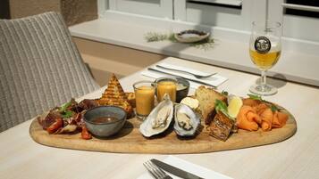 A meal with grilled bread, oysters, smoked salmon, and a glass of wine on a wooden table.