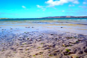 Ein Strand mit klarem Wasser und sanften Hügeln im Hintergrund.
