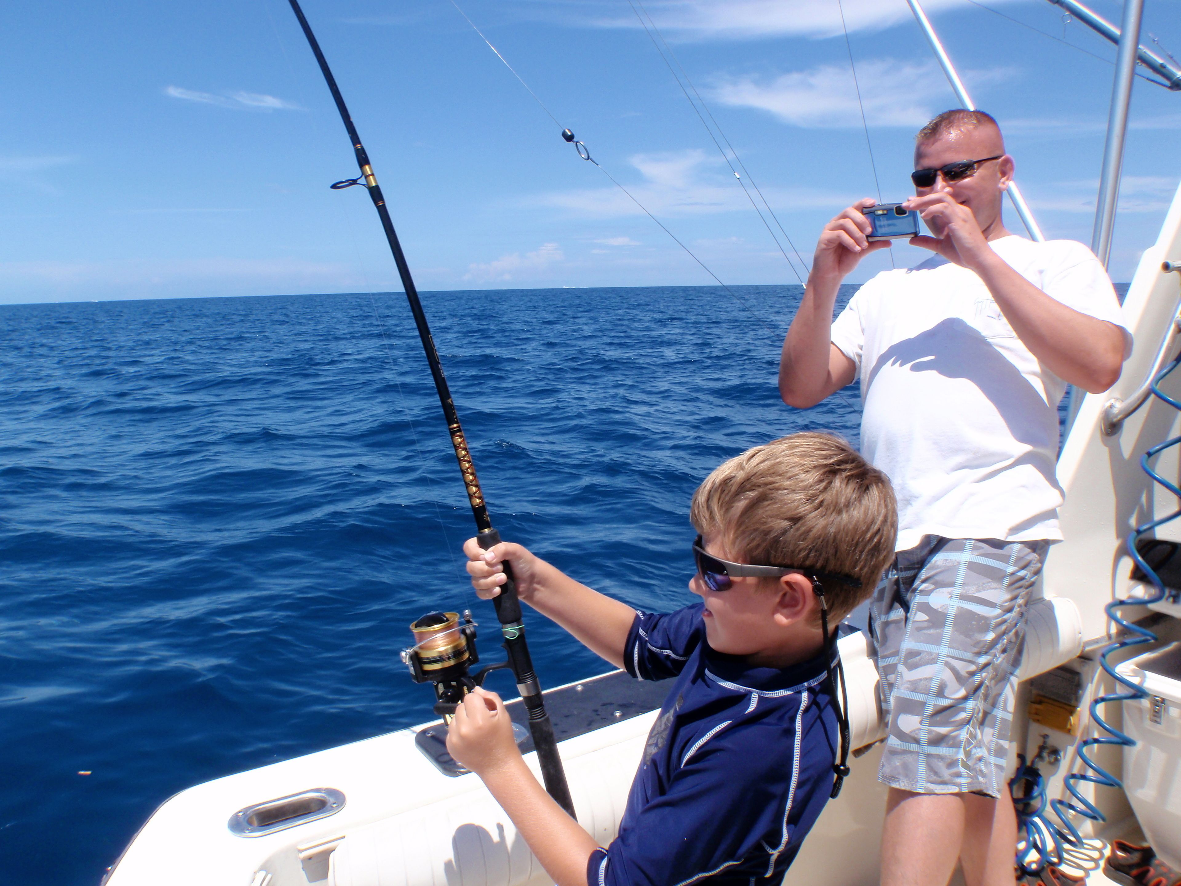 Una barca con una persona che tiene in mano una canna da pesca e un'altra che scatta una foto.