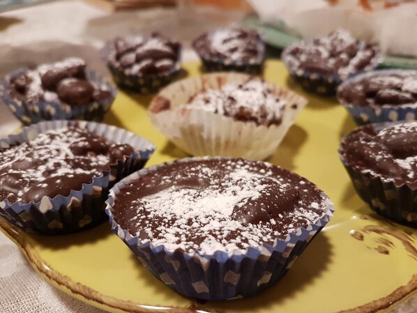 Un plato de cupcakes de chocolate cubiertos de azúcar glas sobre un plato amarillo.
