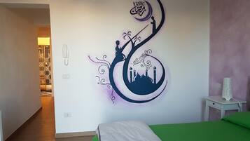 Ein Schlafzimmer mit Bett, Nachttisch und einer Wand mit dekorativem Design.