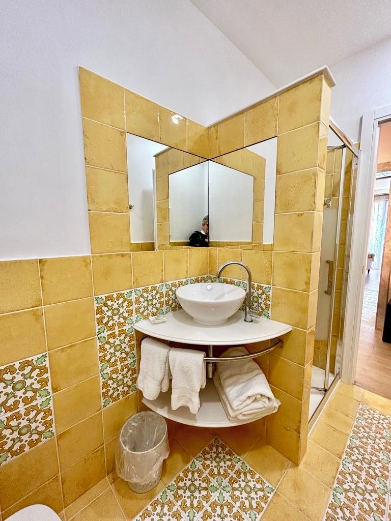 A bathroom with a sink, mirror, and a glass shower enclosure.