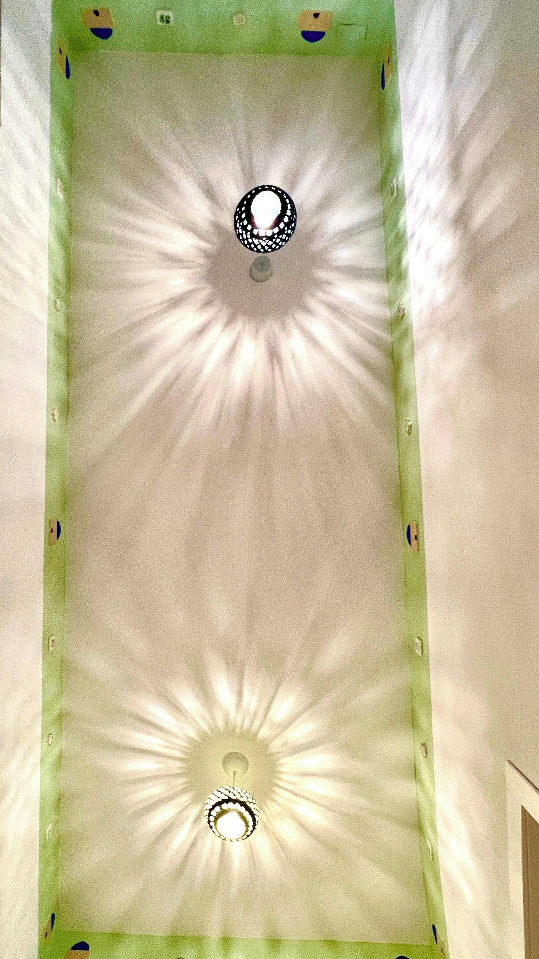A ceiling with a central light fixture and a decorative pattern.