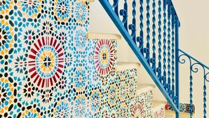 Eine Treppe mit blauen Spindeln und einer Wand mit Muster.