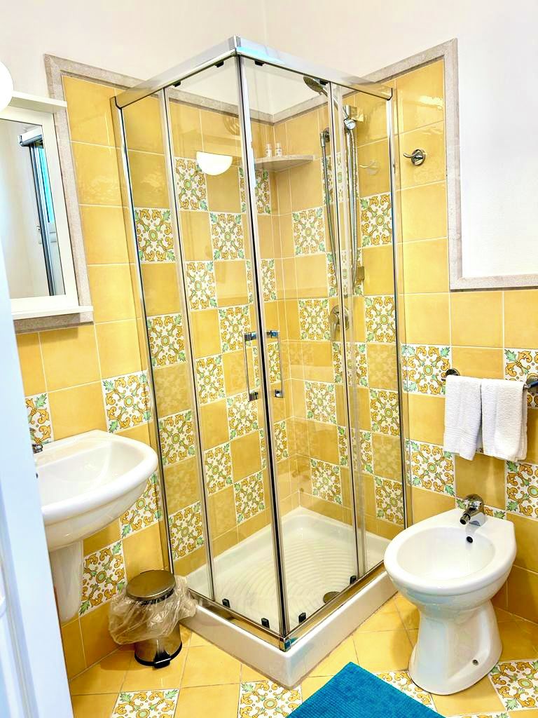 A bathroom with a glass-enclosed shower, a sink, and a toilet.