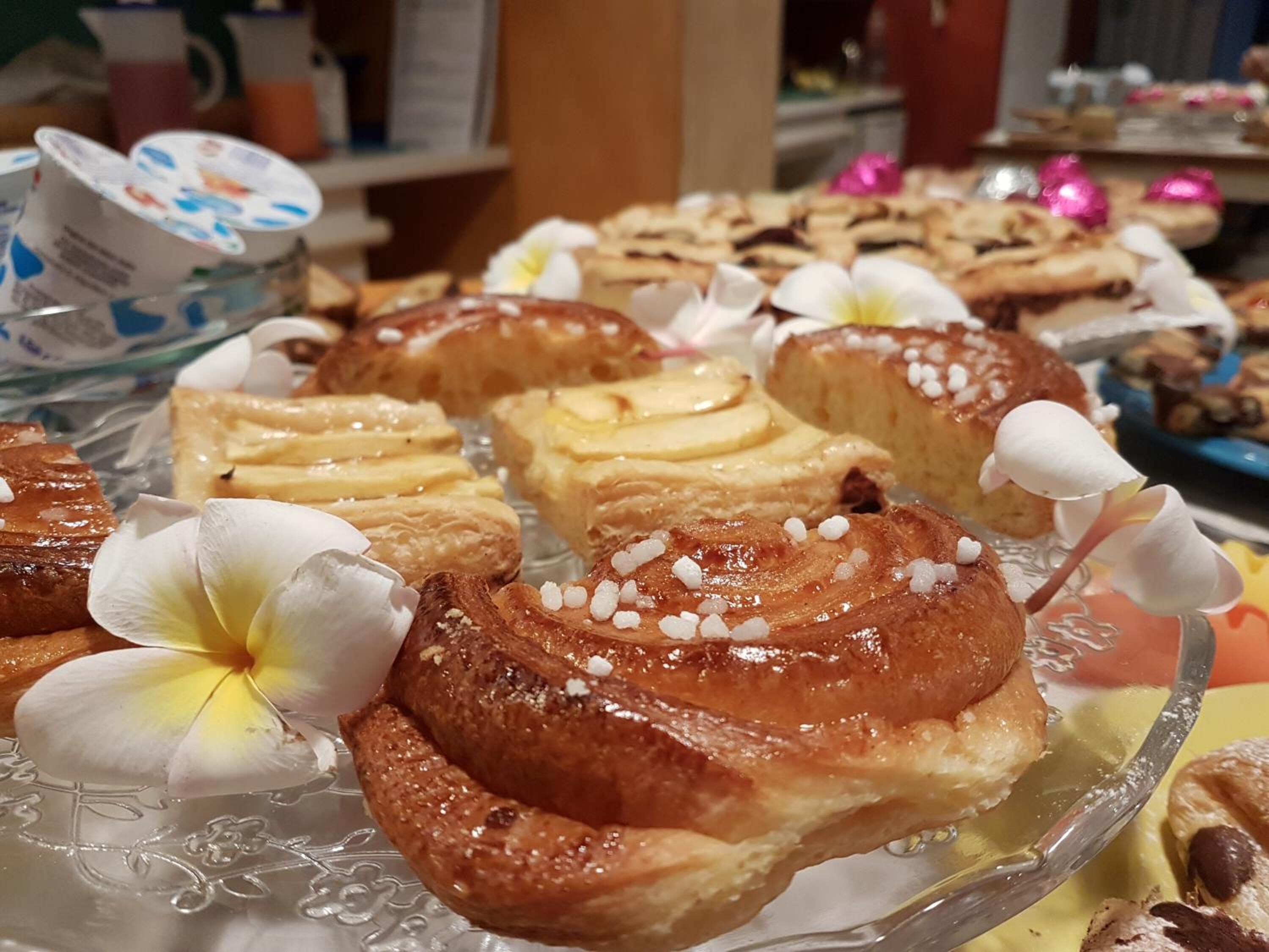 Une variété de pâtisseries et de desserts présentés sur un plateau en verre, agrémentés d’une décoration florale.