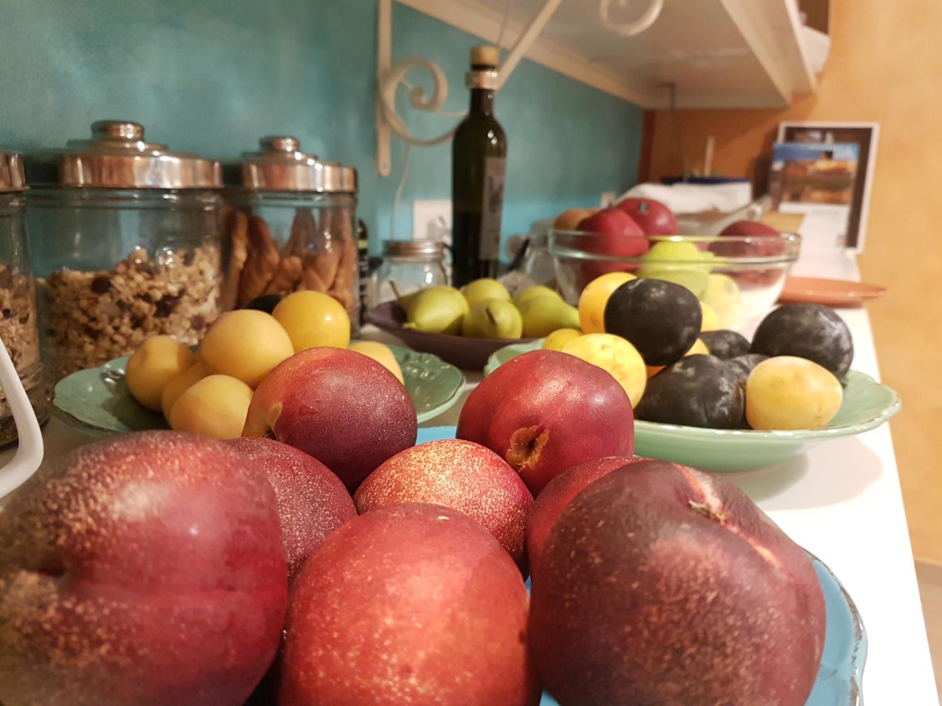 A table with various fruits and snacks, including apples and pears, and a bowl of mixed fruits.