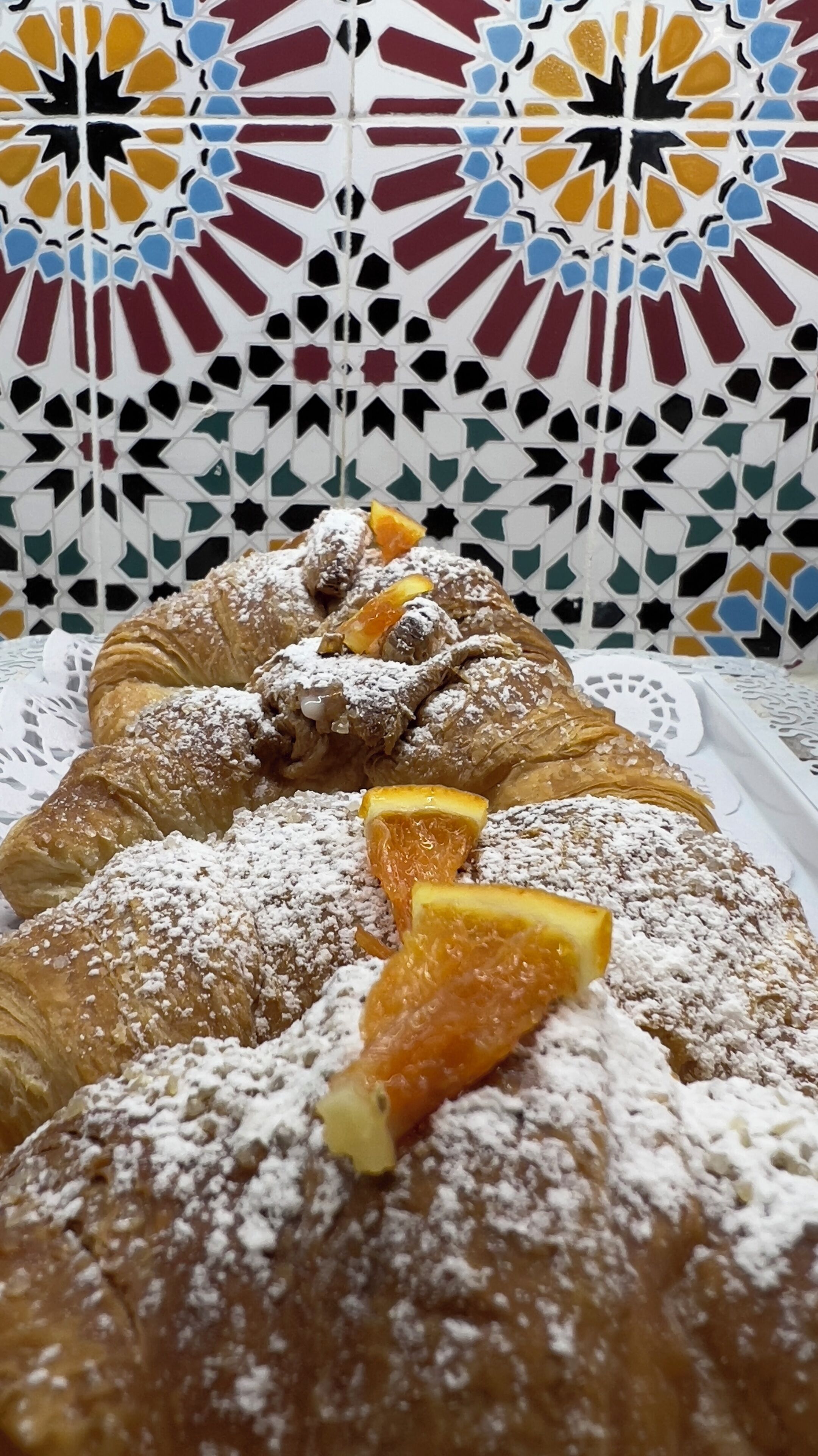 A tray of pastries with powdered sugar and orange slices.