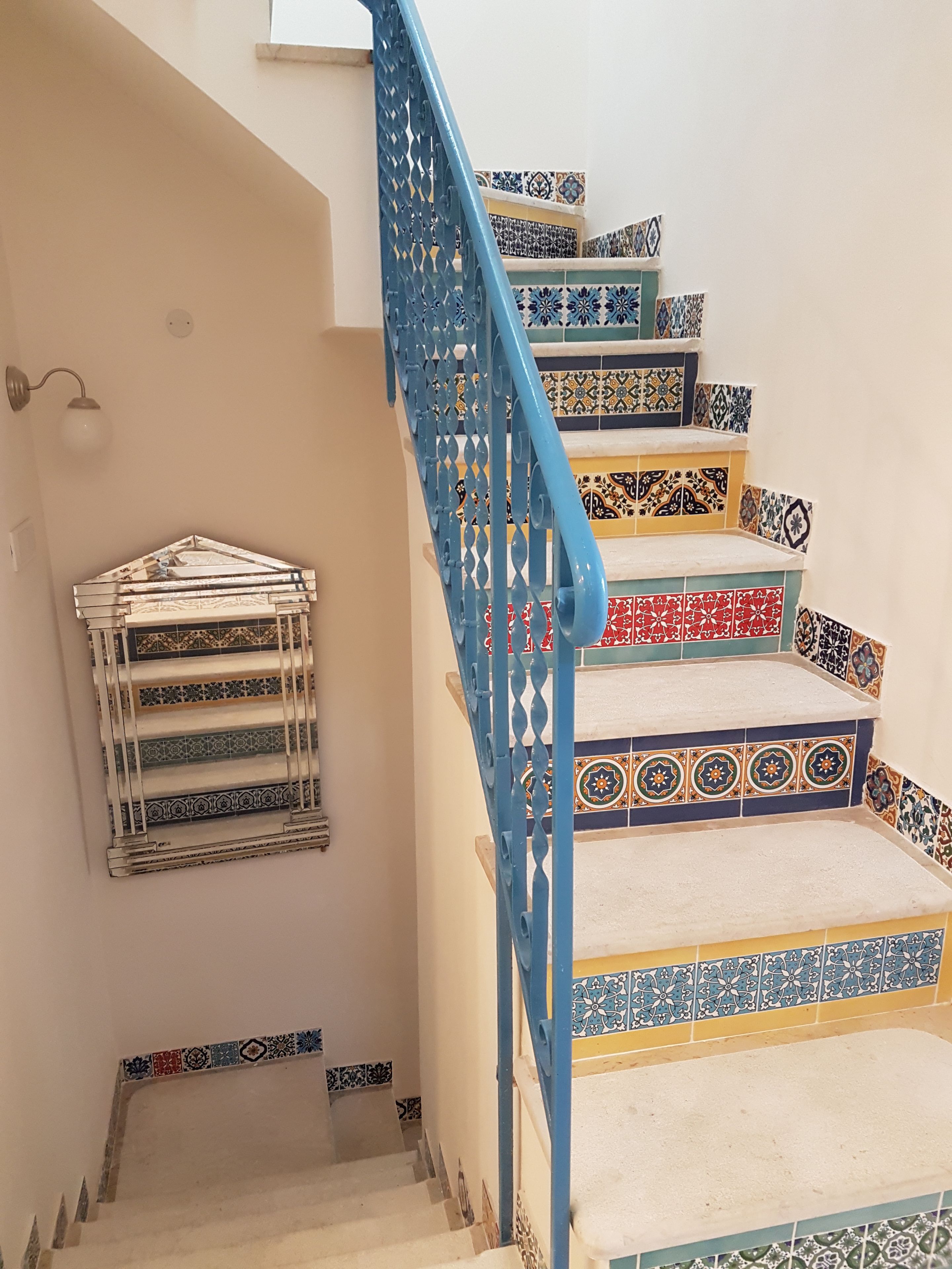 A staircase with blue railings and colorful patterned tiles.