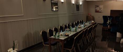 A conference room with a long table, chairs, and a small round table with a vase of flowers.