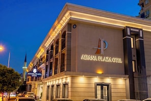 The Adana Plaza Hotel with a prominent sign, a modern facade, and a parking lot visible. - Adana Plaza Otel (Adana)
