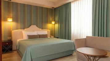 A hotel room with a bed, bedside table, lamp, and a small round table.