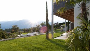 A modern outdoor area with a grassy lawn, a pergola, and a view of distant mountains. - Hidalgo Suites & Restaurant (Postal)