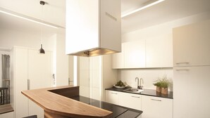 A modern kitchen with a wooden island, white cabinets, and a black countertop. - Hidalgo Suites & Restaurant (Postal)