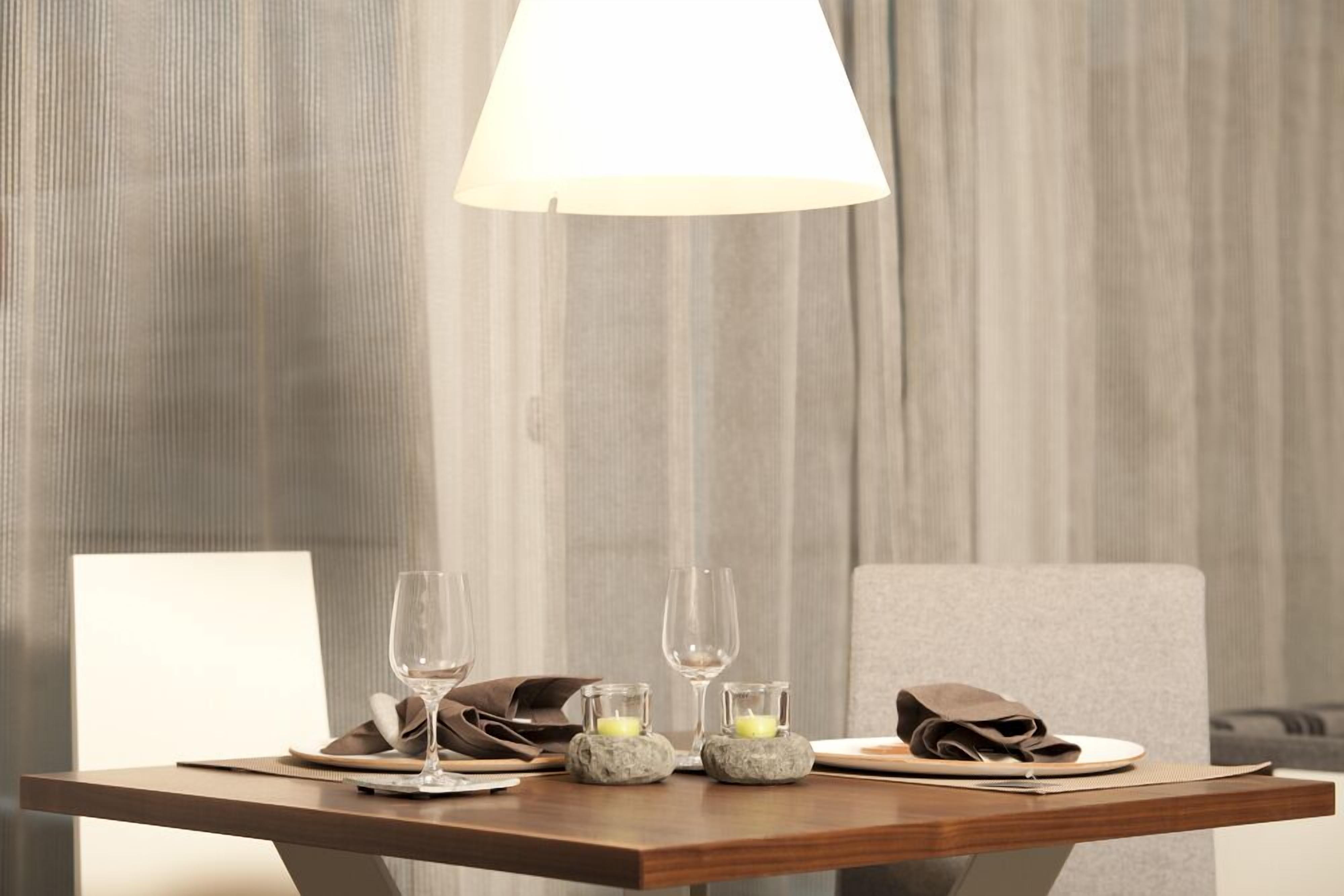 Una mesa de comedor con dos copas de vino, una vela y una servilleta.