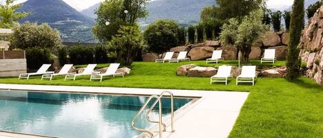 Un espace piscine avec des chaises longues et une vue sur les montagnes.