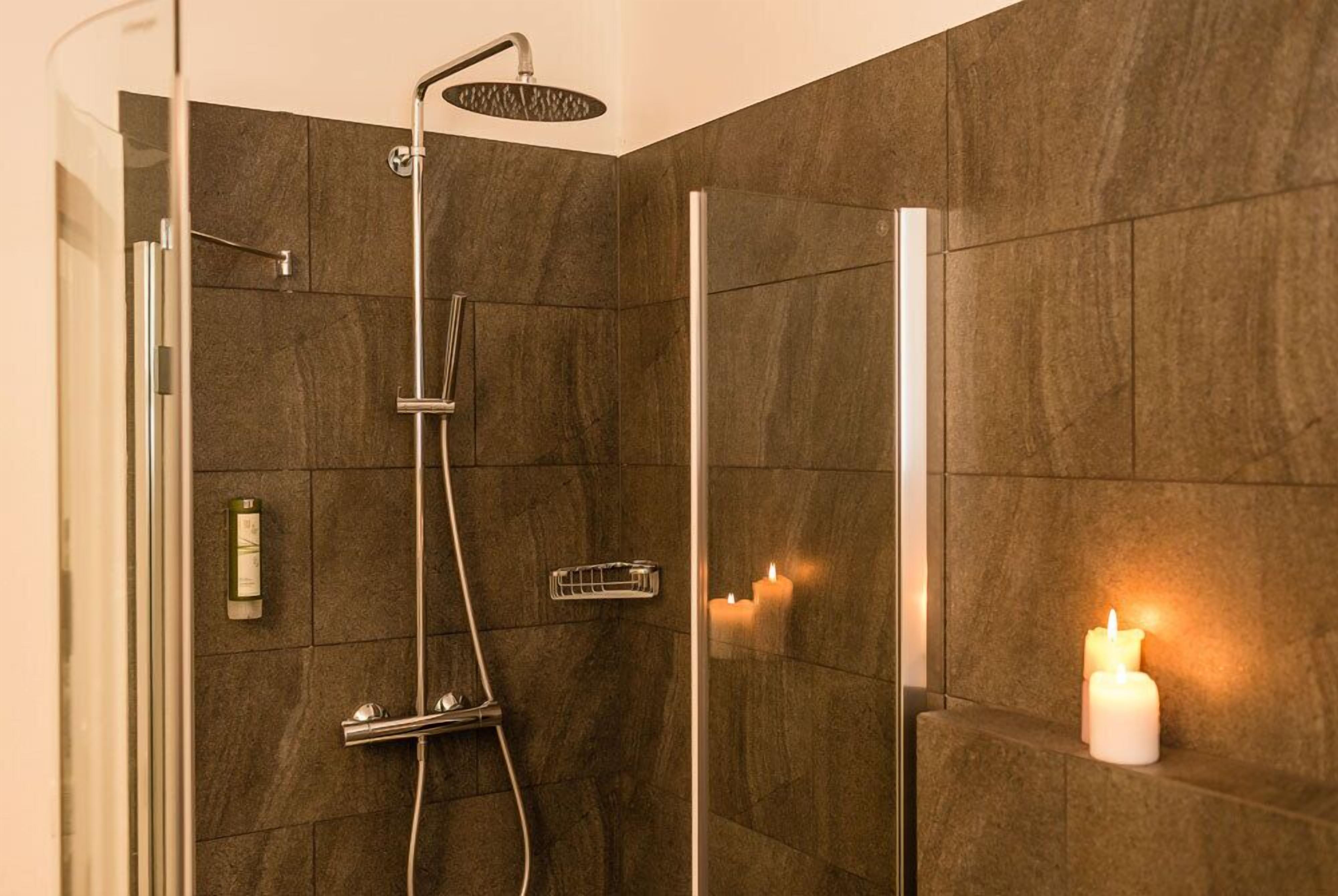 Ein modernes Duschbad mit Glastür, Handbrause und einer fest installierten Bedienpanel.